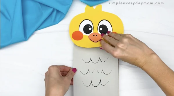 hand gluing body to paper bag bird craft