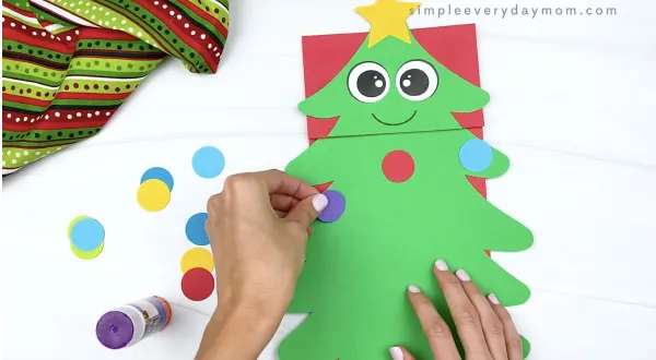 hand gluing ornaments to paper bag Christmas tree craft