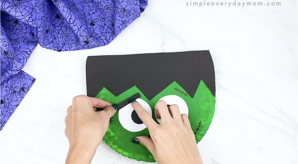 hands gluing eyebrows to paper plate Frankenstein face