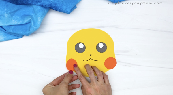hand gluing cheek to paper bag Pikachu craft