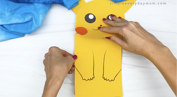 hand gluing body to paper bag Pikachu craft