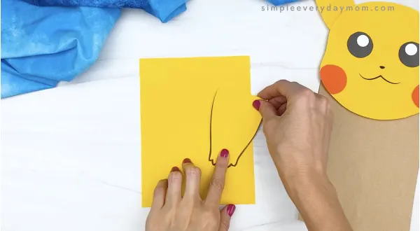 hand gluing arms to paper bag Pikachu craft