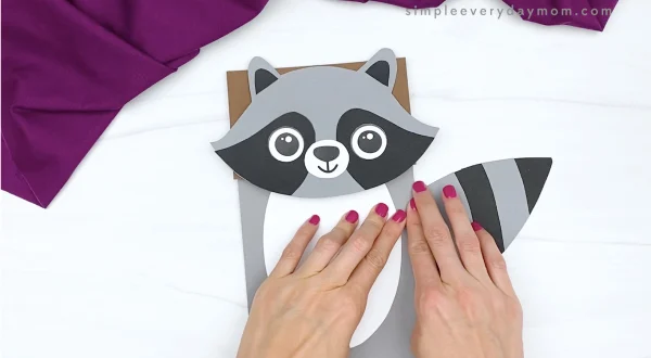 hand gluing tail to paper bag raccoon craft