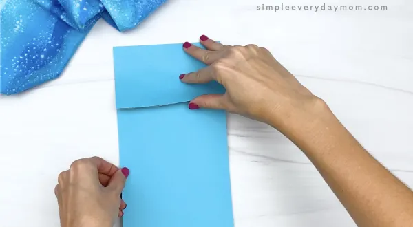 hand gluing blue paper to brown paper bag