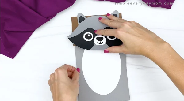hand gluing body to paper bag raccoon craft