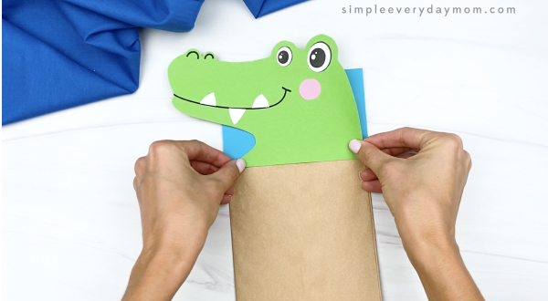 hand gluing head to paper bag alligator craft