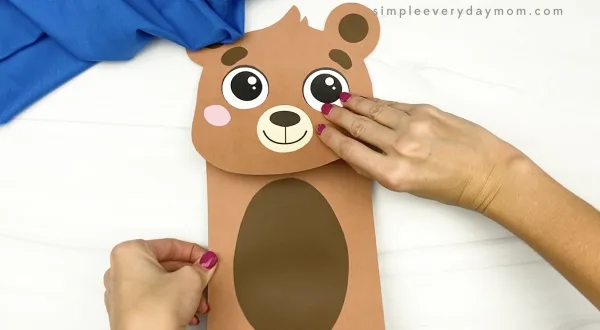hand gluing body to brown bear puppet craft