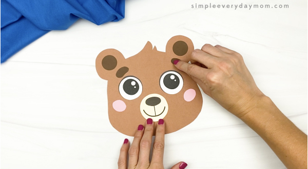 hand gluing eyebrows to brown bear puppet head