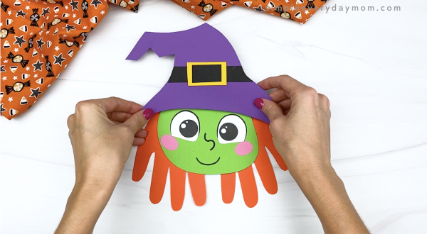 hand gluing witch hat to handprint witch craft