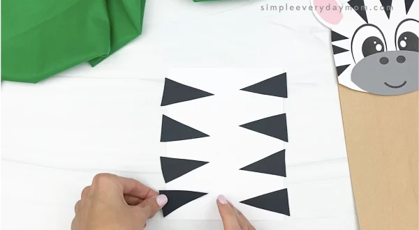 hand gluing stripes to paper bag zebra craft