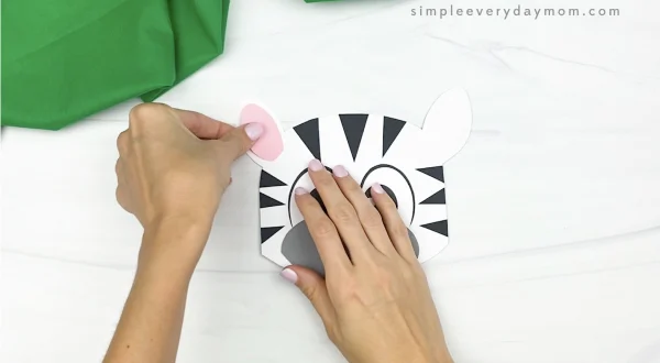 hand gluing inner ear to paper bag zebra craft