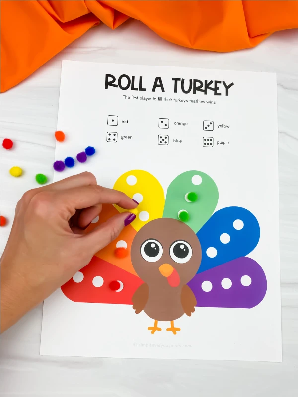hand placing pom pom on roll a turkey game