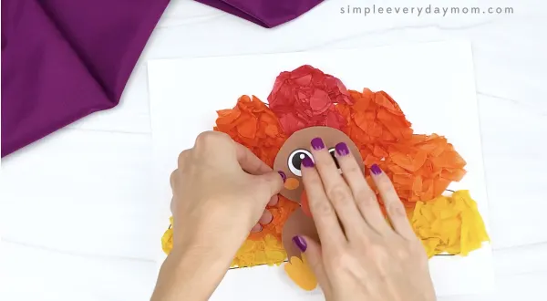 hand gluing turkey to tissue paper turkey craft