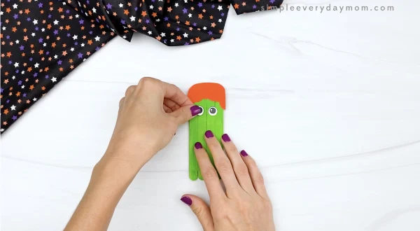 hand gluing eye to popsicle stick witch craft