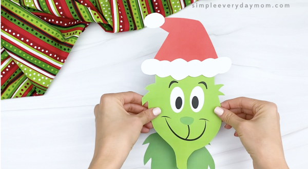 hands gluing head to body of printable Grinch craft