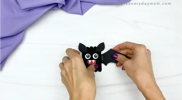 hand gluing wing to popsicle stick bat craft