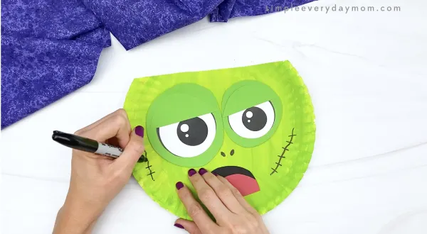 hand drawing stitches onto paper plate zombie craft