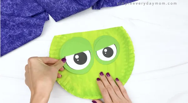 hand gluing eyes to zombie paper plate craft
