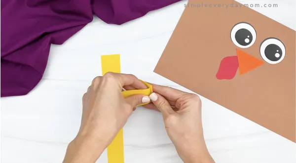 hand folding yellow paper to create turkey legs