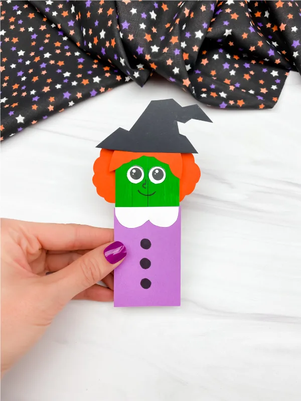 hand holding popsicle stick witch craft