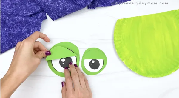 hand gluing eyelid to eyes of paper plate zombie craft