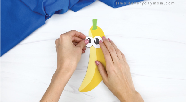hand gluing eyes onto paper banana craft