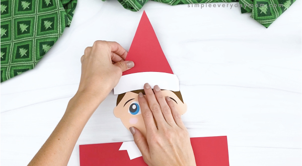 hand gluing hat to elf on the shelf craft