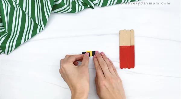 hand gluing inner buckle to popsicle stick Santa
