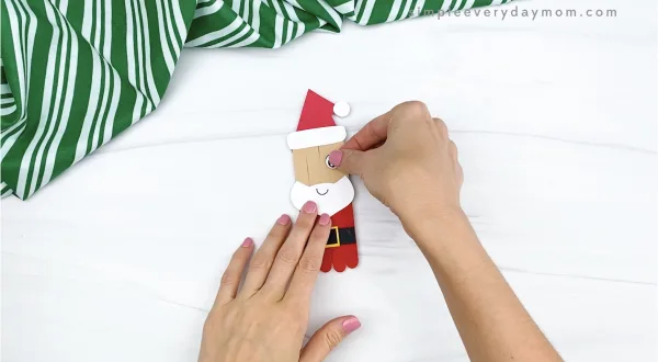 hand gluing eye to popsicle stick santa craft