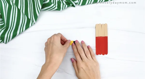 hand gluing outer buckle to popsicle stick Santa