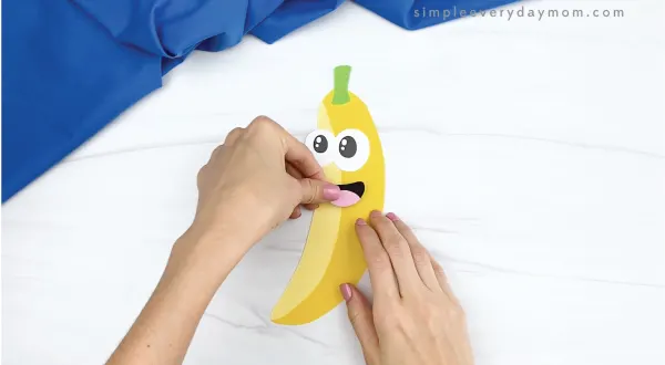 hand gluing mouth onto paper banana craft