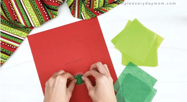 hand gluing dark green tissue paper to grinch craft