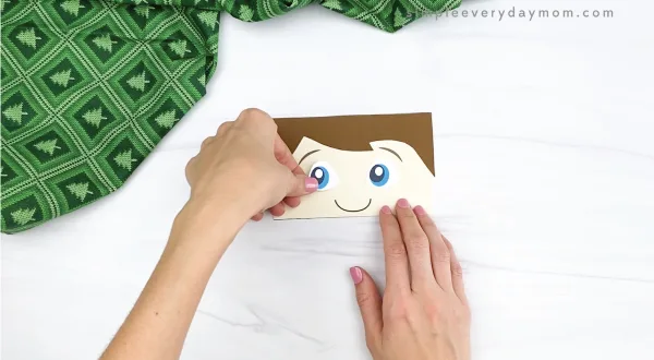 hand gluing eye to elf on the the shelf puppet craft