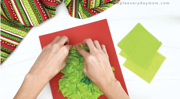 hand gluing green tissue paper to grinch craft