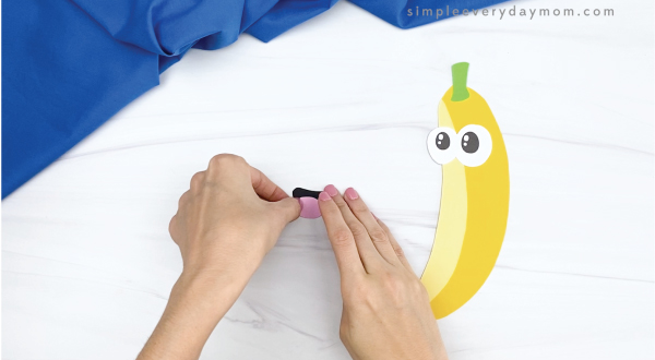 hand gluing tongue to mouth of paper banana craft