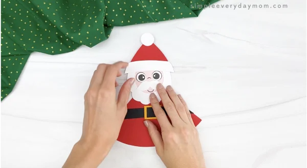hands gluing head to moving Santa craft