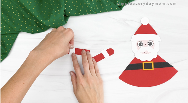 hands gluing arm fluff to moving Santa craft