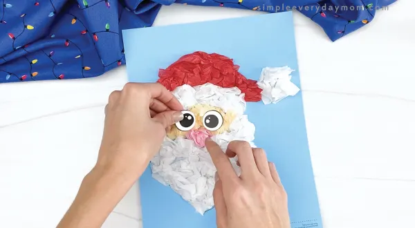 hand gluing eyes to tissue paper Santa craft