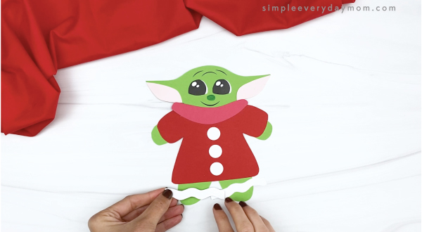hand gluing icing decorations to baby Yoda gingerbread craft