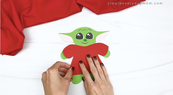 hand gluing coat to baby Yoda gingerbread craft