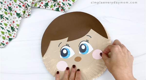 hand gluing cheek to elf on the shelf paper plate craft
