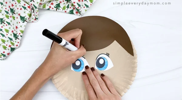 hand drawing eyelashes onto elf on the shelf craft