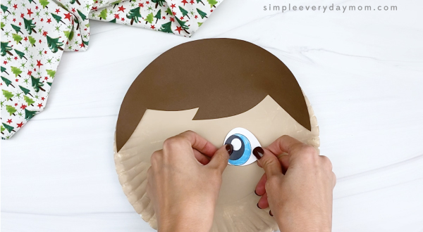 hand gluing eye to elf on the shelf paper plate craft