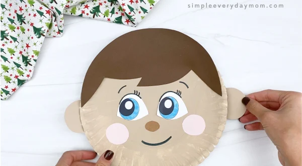 hand gluing ear to elf on the shelf paper plate craft