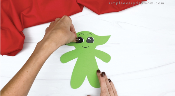 hand gluing eye to baby Yoda gingerbread craft