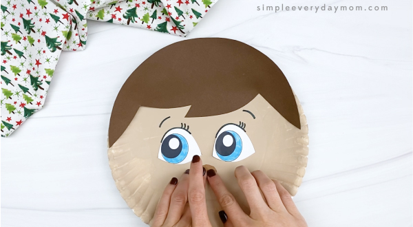 hand gluing nose to elf on the shelf paper plate craft