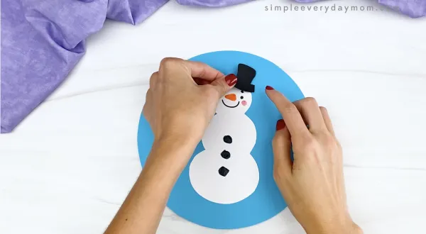 hand gluing hat to snowman snowglobe craft