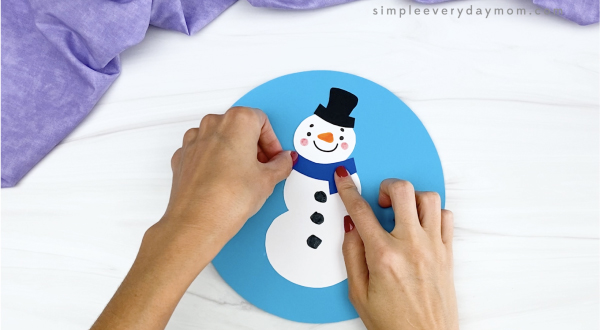hand gluing scarf to snowman snowglobe craft