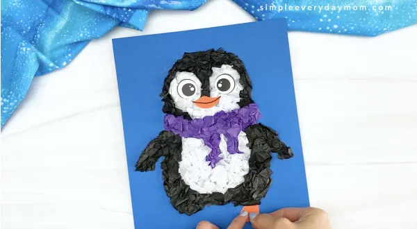 hand gluing foot to tissue paper penguin