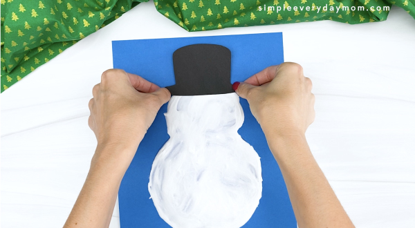 hand gluing hat to puffy paint snowman